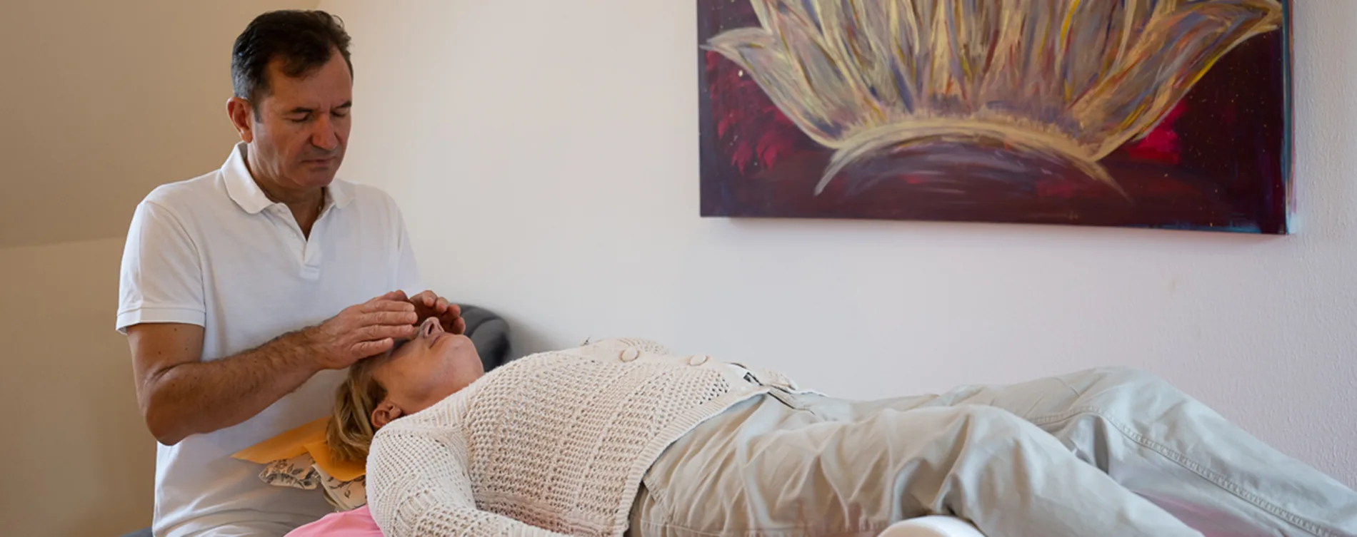 Janni hält bei einer Reiki-Sitzung die Hände über die Augen einer liegenden Frau