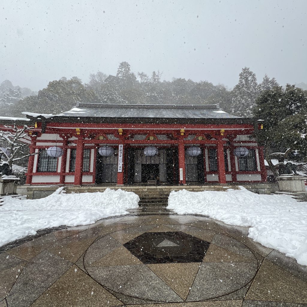 Kuramadera-Tempel auf dem Kurama Berg, dem Geburtsort von Reiki. Ein schöner roter Tempel im Schnee mit einem Energiestein davor